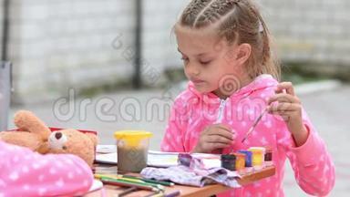 七岁的女孩在一张专辑中选择合适的彩色墨水画，和另一个女孩坐在桌子旁